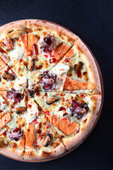 Half seafood pizza on dark background. Top view of delicious pizza with red fish, mussels and octopus.Vertical photo. Flat lay.