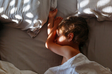 little girl sleeping in parents bed in the morning light