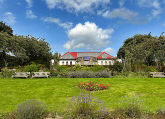 View in Silsden Park, with flowers, grass lawns, wooden benches, and the Bowling Club in the distance in, Silsden, UK