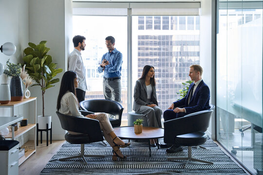 Busy diverse professional team business people workers talking in modern corporate office lobby. Multicultural coworkers group having teamwork conversation together at work meeting. Authentic shot