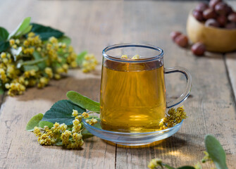 Fresh lime blossoms and freshly brewed lime tea on the table. Aromatic and medicinal herbal tea concept