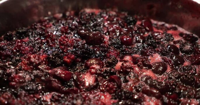 The process of cooking plum and blackberry jam.