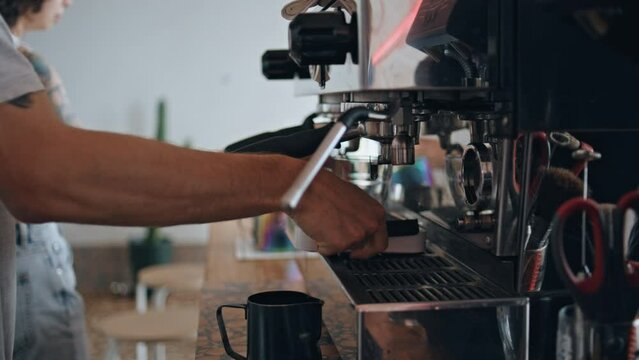 Barista hands making coffee with modern coffee machine in cafeteria close up.