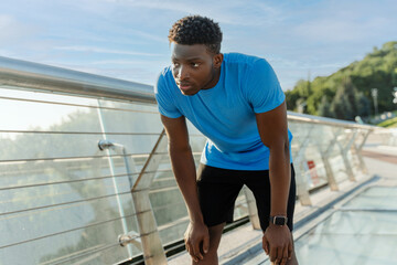 Portrait of tired, serious African American sportsman standing after running, training outdoors