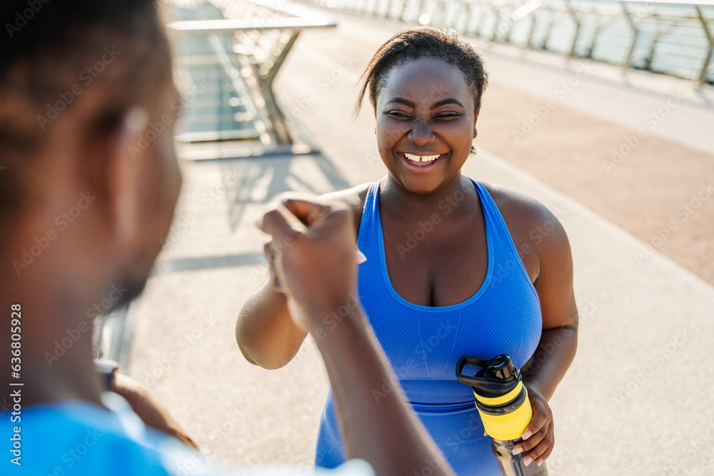 Wall mural positive african american couple talking after working out outdoors. training, healthy lifestyle