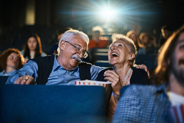 Senior couple watching a movie and eating popcorn in a movie theater