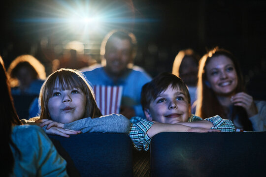 Young family watching a movie and eating popcorn in a movie theater