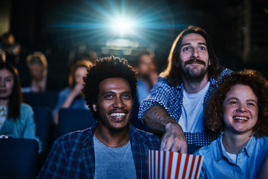 Young diverse group of friends watching a movie together in the movie theater