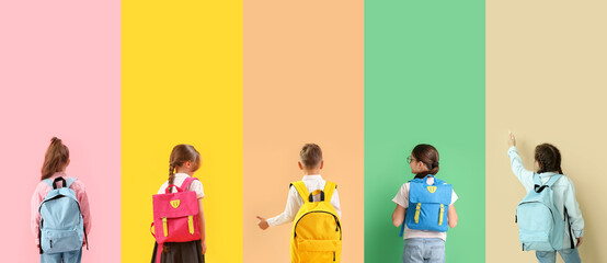 Group of little school children with backpacks on color background, top view