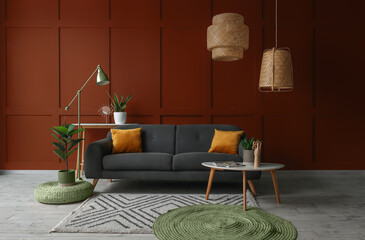 Interior of living room with stylish sofa, tables and lamps near brown wall