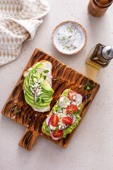 Avocado toasts with radishes, tomatoes and feta topped with olive oil
