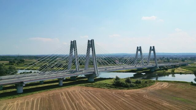 Monumental, lighted, new modern suspension cable bridge over Vistula River in Krakow, Poland during summer. Eastern Europe critical infrastructure highway. Downtown aerial cityscape.