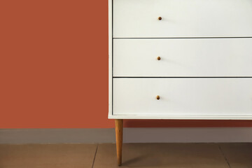 White chest of drawers near color wall, closeup