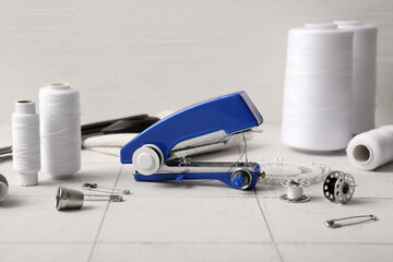 Manual sewing machine with different supplies on white tile near wall