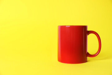 One red ceramic mug on yellow background. Space for text