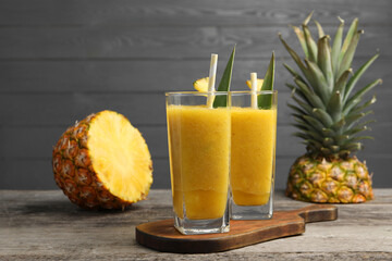 Tasty pineapple smoothie and cut fruit on wooden table