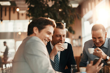 Group of businessmen enjoying a coffee and using a smart phone after work in a cafe bar decorated...