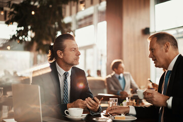Two businessman having coffee and a meeting in a cafe bar decorated for christmas and the new years holidays
