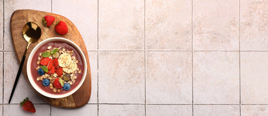 Smoothie bowl with muesli, banana and berries on tiled table, top view. Banner design with space...