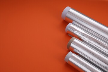 Rolls of aluminum foil on red background, closeup. Space for text