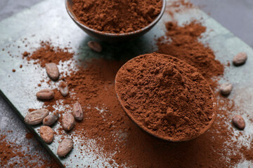 Bowls with cocoa powder and beans on table