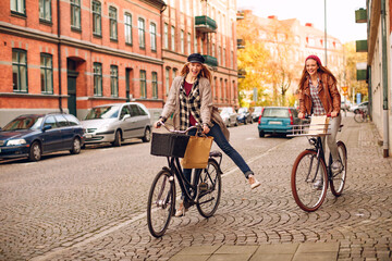 Obraz na płótnie Canvas Young lesbian couple shopping and riding their bicycles in the city
