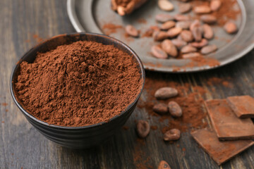 Bowl with cocoa powder on wooden background