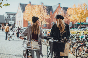 Young lesbian couple shopping and pushing their bicycles on a city street