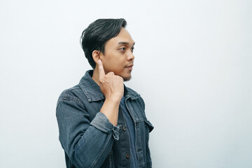 Portrait of Indonesian Asian man point his index finger on ear showing deafness gesture. Isolated white background