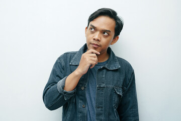 Portrait of Asian Indonesian man serious thinking gesture. Wears black denim jacket casual concept
