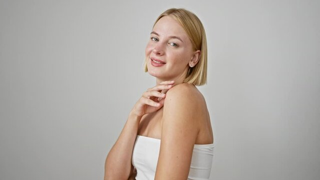 Young blonde woman smiling confident touching face over isolated white background