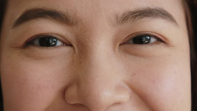 Close-up black iris eyes upper facial of young female asia people Gen Z teen girl looking at camera smile mental health. Natural beauty make up botox skin care in happy adult lady vision hope focus.