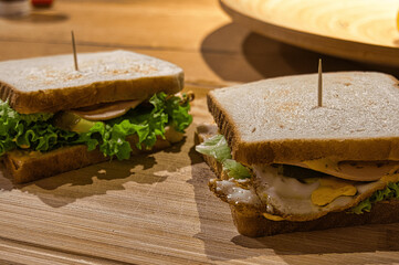 Foto von einem Sandwich mit Tomate, Ei, Gurke und Salat auf einem Brett mit Zahnstocher. Photo of a sandwich with tomato, egg, cucumber and lettuce on a board with toothpick