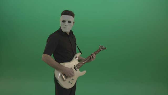 Rock man in white mask and black wear playing guitar isolated on green screen in side view