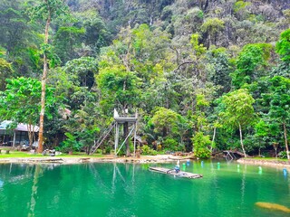 Clear lake surrounded by trees. The trees are mostly evergreens In Vangvieng District, Laos.