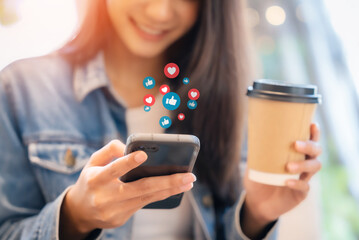 Young asian women watching live streaming video in a cafe coffee shop. Happy female using mobile smartphone social media application for entertainment