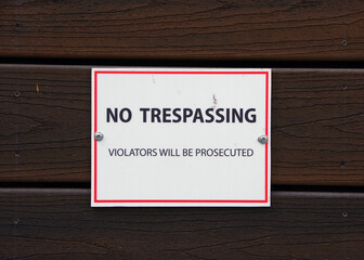 NO TRESPASSIGN sign on a wooden building wall