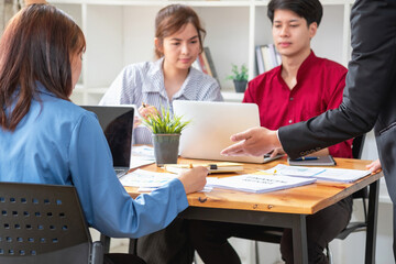 Asian business team consists of marketing staff. accountant and financial officer Help each other analyze company profits using tablets. calculator Laptop computers, graph paper, and corporate pens.