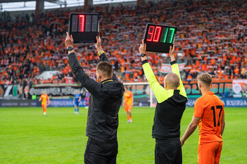 Technical referee shows added time and second man shows players substitution during football match.
