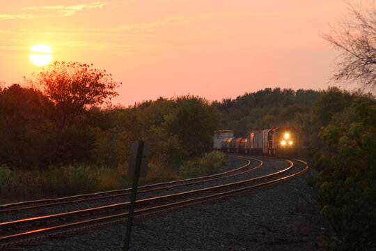 A freight train rounds a curve as the sun sets
