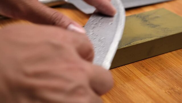 Sharpening knives with a Whetstone. Knife sharpening. Sharp knife and sharpening stone on a wooden cutting board.