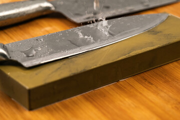 Sharpening knives with a Whetstone. Knife sharpening. Sharp knife and sharpening stone on a wooden...