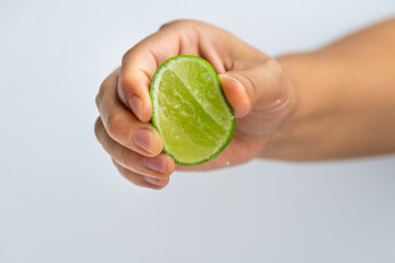 Female hand squeezing half fresh lemon isolated on white background. Squeezing fresh lemon close...