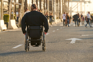 Obraz premium person in wheelchair at sunset on street in Malaga harbour in Spain
