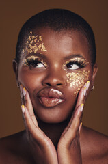 Art, fun and black woman in gold makeup on brown background, glitter paint or cosmetics. Shine, glow and silly face of African model in studio for beauty, fashion and aesthetic freedom in luxury skin