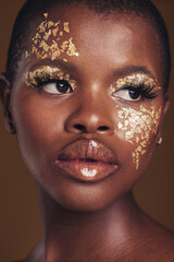 Art, face of black woman with gold makeup and brown background, glitter paint and cosmetics. Shine, glow and African model in studio on facial beauty, fashion and aesthetic freedom in luxury skincare