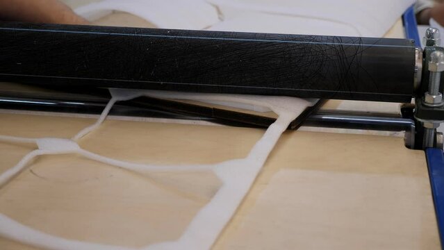 Close-up of a special machine for rolling sintepon in the atelier for the production of bags.