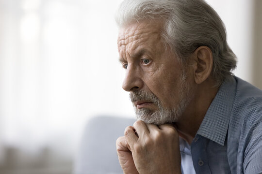 Concerned thoughtful older retired man looking away, leaning chin on hands, thinking over healthcare problems, retirement, suffering from mental disease, memory loss. Face portrait, side view