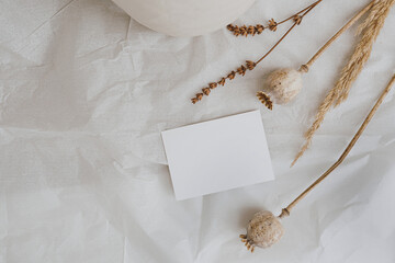 Blank paper card sheet with empty free copy space for mock up. Dried grass, poppy stems and clay...