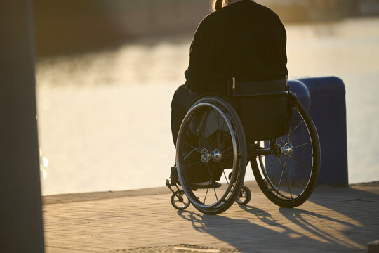 disabled person in wheelchair in harbor looking at sunset in Malaga Spain